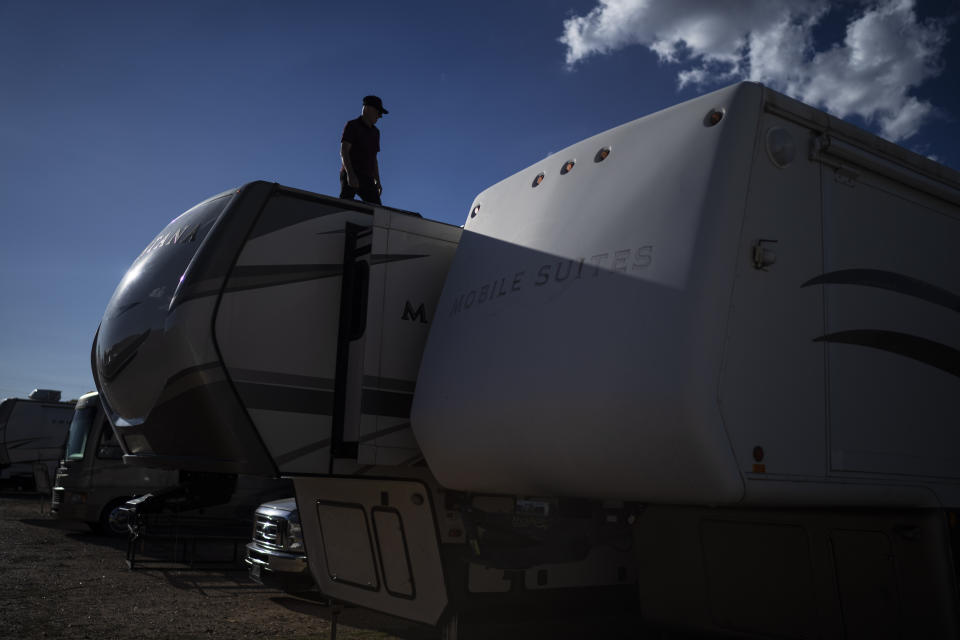 Lonnie Phillips inspects the roof of the RV he and his wife, Sandy, used to travel from one mass shooting to another, as it sits in a storage lot in Longmont, Colo., Monday, Sept. 4, 2023. Some people Sandy met along the way stayed in touch for years; others dissolved into tears in her arms, never to be heard from again. Some spiraled to suicide. Some of their tragedies were seared into public consciousness; others receded into a jumble of places where something awful happened, but few seemed to remember exactly what. (AP Photo/David Goldman)