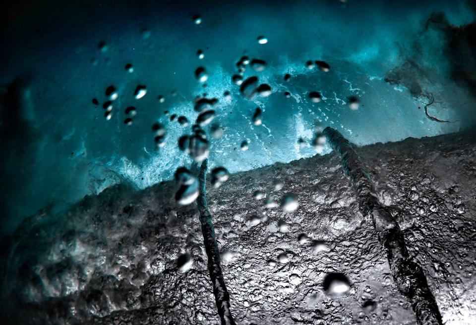 <p>Under a rolling wave during stormy conditions at the island of Oahu. (Photo: Marco Mitre/Caters News) </p>