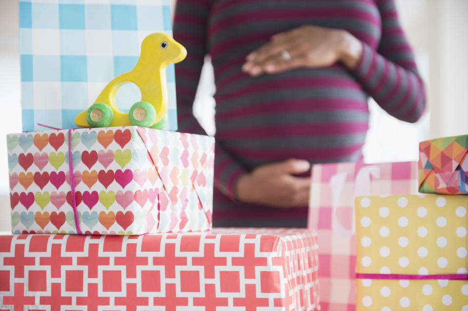 A pregnant woman standing behind presents