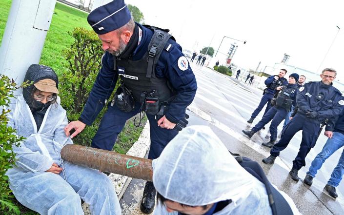 Un policier parle à un manifestant du changement climatique devant l'entrée de la raffinerie Total à Mardyck, près de Dunkerque, dans le nord de la France - François Lo Presti/AFP via Getty Images