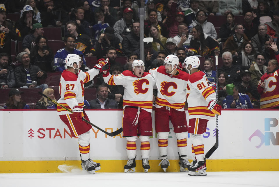 Calgary Flames' Nick Ritchie, Troy Stecher, Dennis Gilbert and Nazem Kadri, from left, celebrate Stecher's goal against the Vancouver Canucks during the second period of an NHL hockey game Friday, March 31, 2023, in Vancouver, British Columbia. (Darryl Dyck/The Canadian Press via AP)