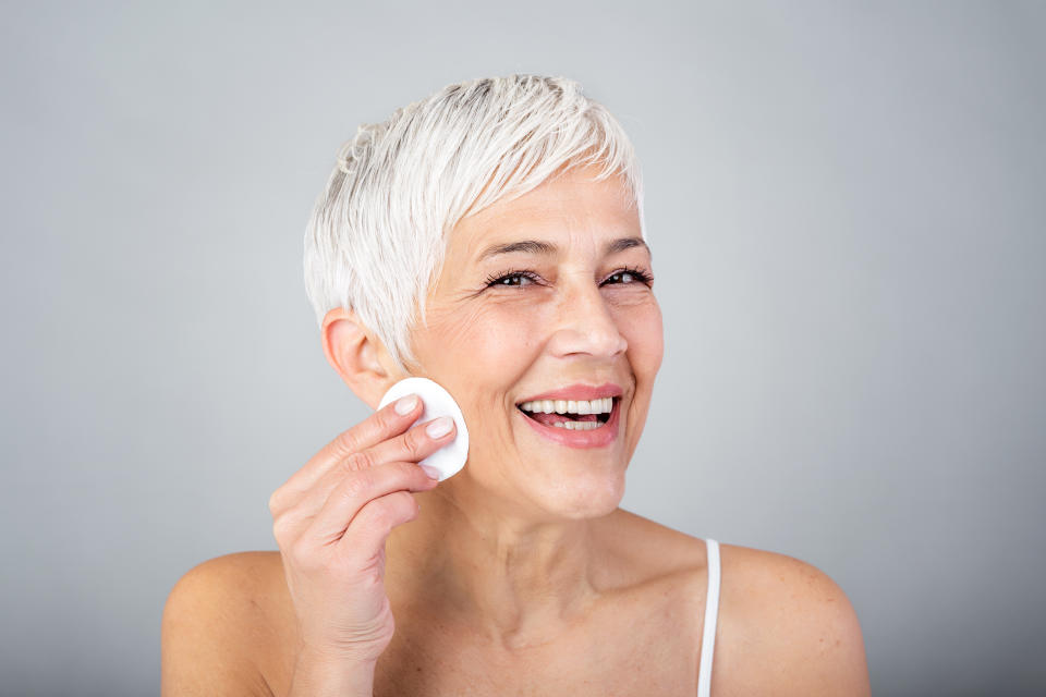 Woman applying a chemical exfoliant to her face, one recommendation to use for menopause skin care