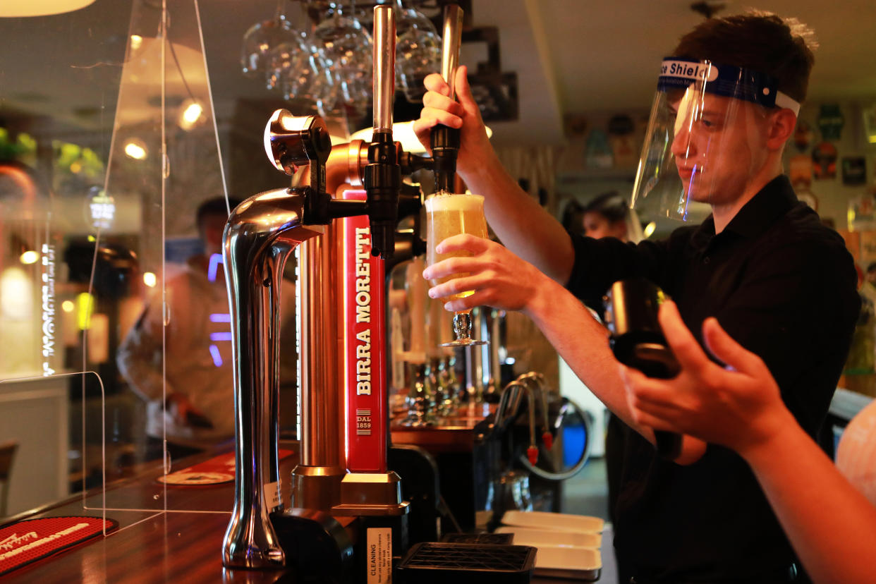 A member of staff wearing a PPE visor pours a pint inside the Black Horse Inn in Haxby, York, on Super Saturday as pubs and other stores reopen after lockdown measures are relaxed in England