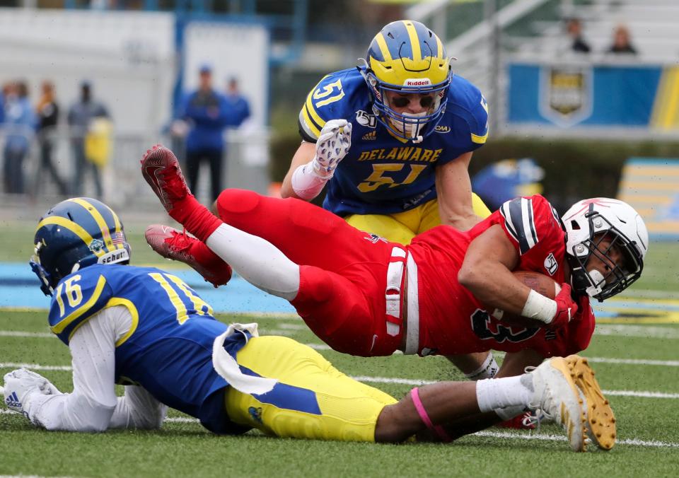 Delaware defensive back Nijuel Hill (left) tackles Richmond's Aaron Dykes after a reception as linebacker Drew Nickles moves in during the fourth quarter of Delaware's 35-25 loss at Delaware Stadium in 2019.