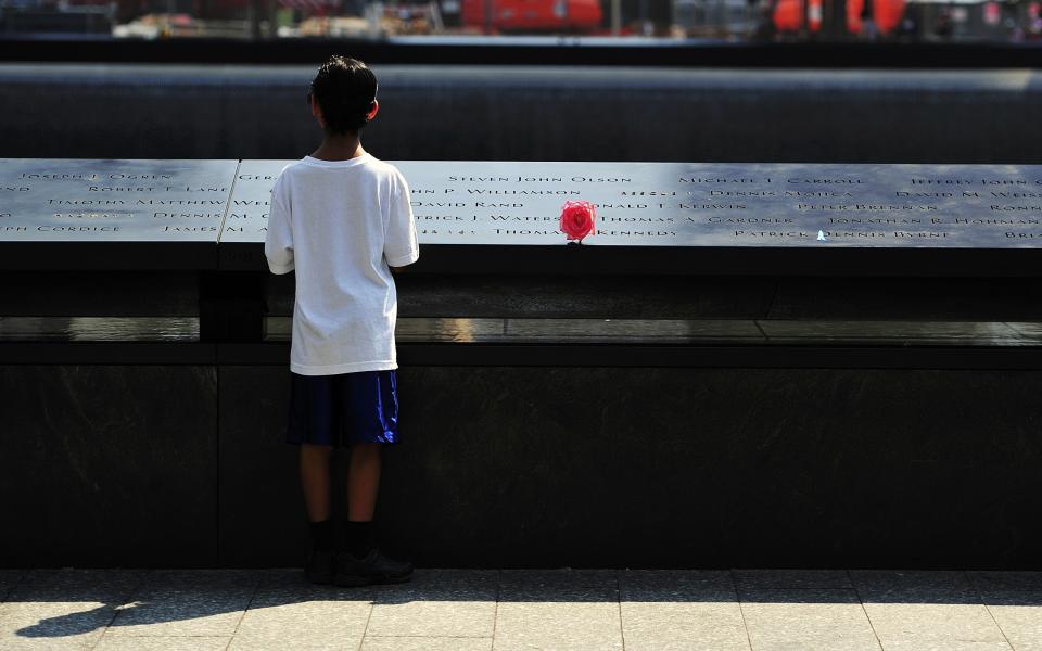 A boy looks at names on the South reflecting pool at the 9/11 Memorial during ceremonies marking the 12th anniversary of the 9/11 attacks on the World Trade Center in New York, September 11, 2013. REUTERS/Stan Honda/Pool (UNITED STATES - Tags: ANNIVERSARY DISASTER)