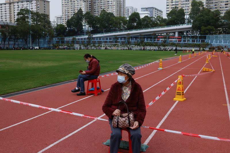 People sit on stools as they wait at a community testing centre for the coronavirus disease (COVID-19), in Tuen Mun, Hong Kong