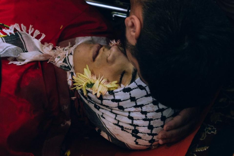 Ahmad Mutair, 17, is bid farewell by members of his family before being laid to rest on Oct. 25. Earlier that day, dozens of Israeli forces entered Qalandia camp in an early morning raid. Ahmad was standing on his roof when an Israeli sniper shot a bullet that pierced his chest and exited from his back. Ahmad was a fourth-generation refugee. After Ahmad was shot, his family spent over 30 minutes trying to take him to a nearby hospital outside Qalandia refugee camp. Israeli forces did not allow Ahmad’s family to leave. Eventually they found an ambulance on the outskirts of the camp which took Ahmad’s body to the Ramallah hospital, where he was pronounced dead. <span class="copyright">Maen Hammad</span>