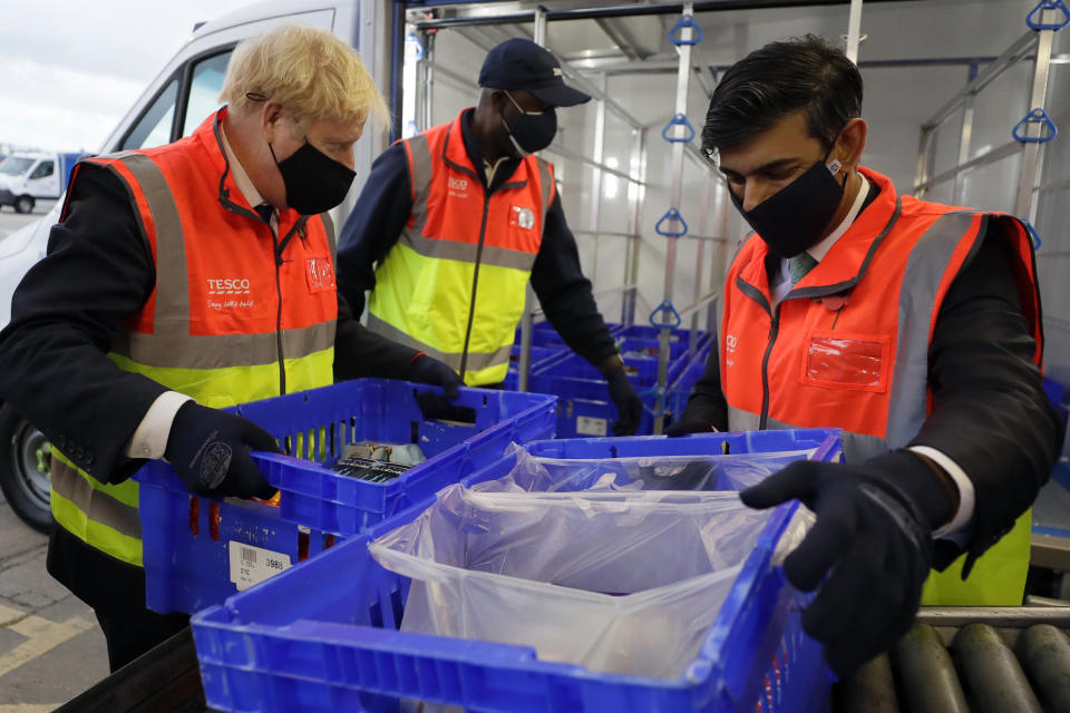 Britain's Prime Minister Boris Johnson and Chancellor Rishi Sunak load a delivery van with baskets of shopping during a visit to a tesco.com distribution centre in London, Wednesday, Nov. 11, 2020. (AP Photo/Kirsty Wigglesworth, pool)