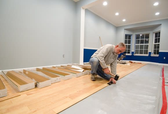 Installer laying wood laminate flooring.