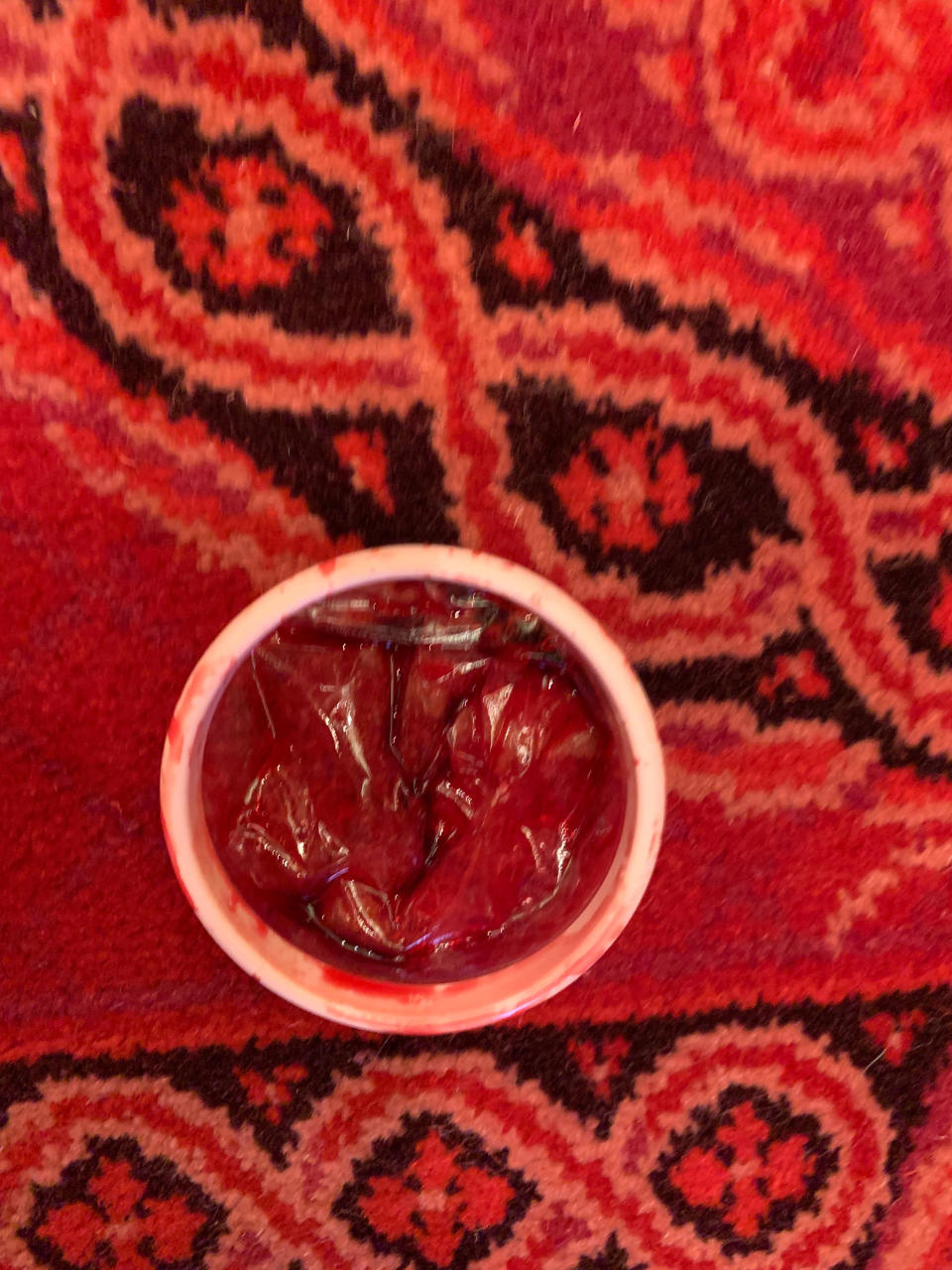 In this photo provided by state Senator Steven Glazer, a container with red liquid sits on the carpet of the state Senate after a woman threw the container from the public gallery of the Senate chambers during a legislative session, in Sacramento, Calif., Friday, Sept. 13, 2019. The woman was taken into custody and the Senate chambers was cleared as an investigation was conducted. (Senator Steven Glazer via AP)