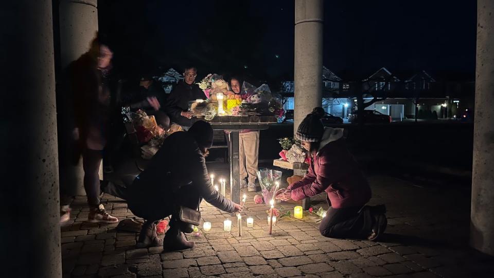 People lay flowers and light candles at park near the crime scene at Berrigan Drive in Ottawa on March 7, 2024.