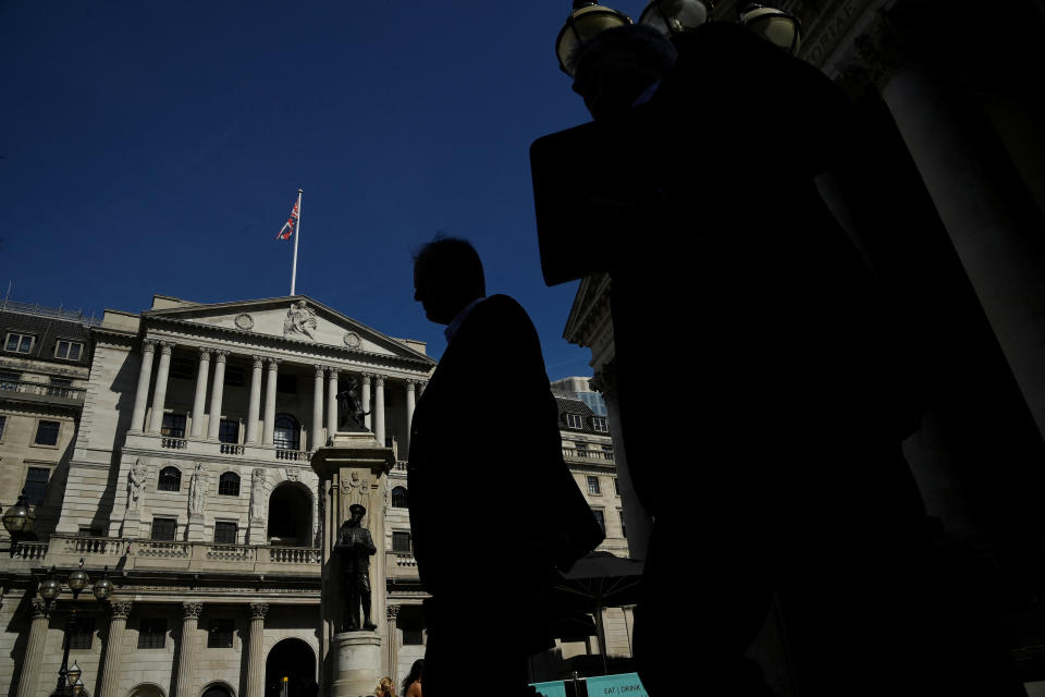 Workers are silhouetted as they walk past the Bank of England