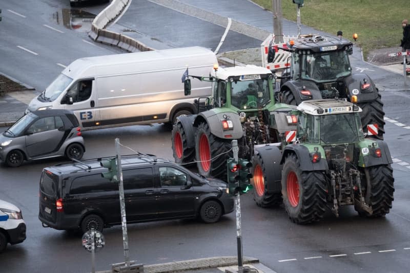 Tractors stand in rush-hour traffic on Karl-Marx-Allee as they drive to a demonstration in the direction of the Brandenburg Gate. According to the police, around 10000 participants and 5000 vehicles are expected to take part in a large demonstration by farmers' associations and the BGL haulage association against planned subsidy cuts by the federal government, including for agricultural diesel. Sebastian Christoph Gollnow/dpa
