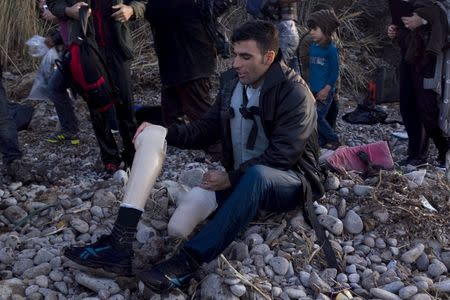 An Afghan refugee prepares to put on his prosthetic leg moments after arriving on an overcrowded dinghy on the Greek island of Lesbos, after crossing a part of the Aegean Sea from the Turkish coast, October 8, 2015. REUTERS/Dimitris Michalakis