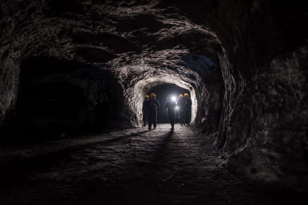 Group of men in a dark mine underground - mining concepts