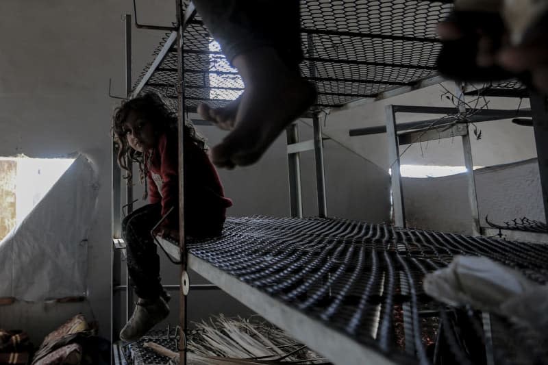 A displaced Palestinian child looks on while residing with her family inside a poultry farm. Due to a lack of a tent, the family was forced to live in a poultry farm. Mohammed Talatene/dpa