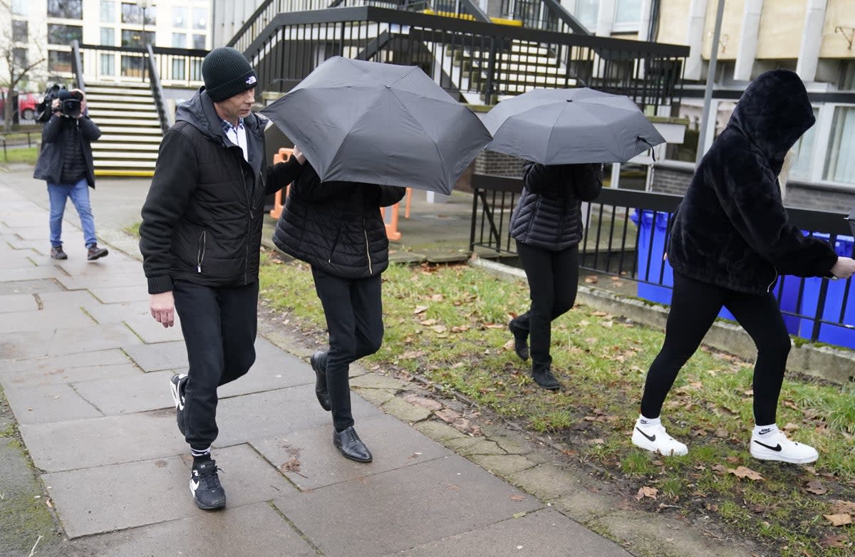 Elliot Benham, 23, (second left under umbrella) and Sophie Harvey, 23, (second right under umbrella) leave Cheltenham Magistrates' Court during an earlier hearing  (PA)