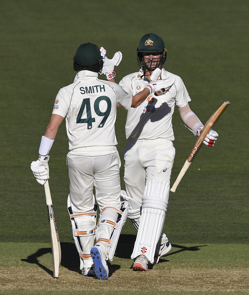 Australia's Joe Burns, right, is congratulated by teammate Steve Smith after hitting a 6 to win their cricket test match against India on the third day at the Adelaide Oval in Adelaide, Australia, Saturday, Dec. 19, 2020. (AP Photo/David Mariuz)