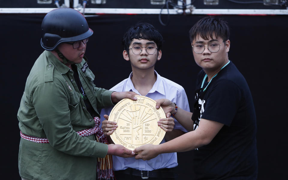 Pro-democracy student leaders hold a plaque declaring "This country belongs to the people" at the Sanam Luang field during a protest in Bangkok, Thailand, Sunday, Sept. 20, 2020. Thousands of demonstrators turned out Saturday for a rally to support the student-led protest movement's demands for new elections and reform of the monarchy. (AP Photo/Sakchai Lalit)