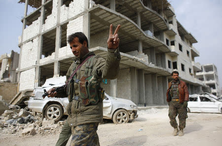 A fighter of the Kurdish People's Protection Units (YPG) flashes a V-sign as he patrols in the streets in the northern Syrian town of Kobani January 28, 2015. REUTERS/Osman Orsal