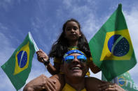 A father and his daughter attend a campaign event for Brazil's President Jair Bolsonaro, who is running for reelection, in Brasilia, Brazil, Saturday, Oct. 29, 2022. Bolsonaro is facing former President Luiz Inacio Lula da Silva in a runoff election set for Oct. 30. (AP Photo/Eraldo Peres)