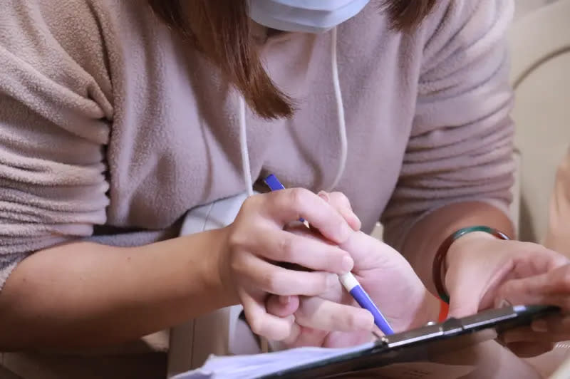 ▲黃先生的太太握著黃先生的手，簽署捐腦同意書。（圖／台大醫院提供）