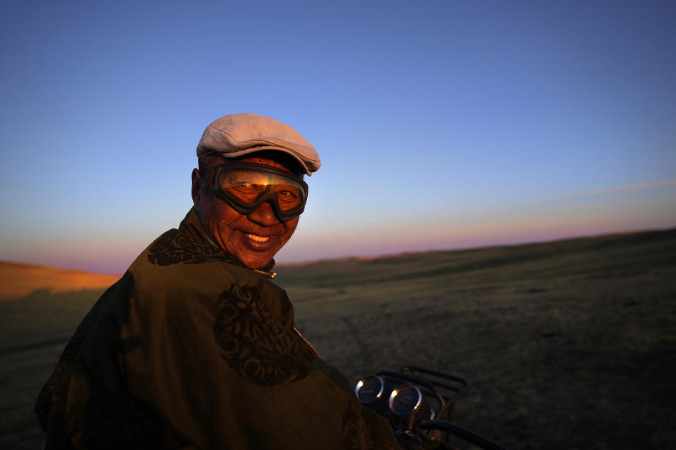Lkhaebum, 71, sets out at dawn to look for his two hundred horses in the sprawling grasslands of the Munkh-Khaan region of the Sukhbaatar district in southeast Mongolia, Saturday, May 13, 2023. He recently began using a motorbike to more easily search for horses, which are never kept fenced. (AP Photo/Manish Swarup)