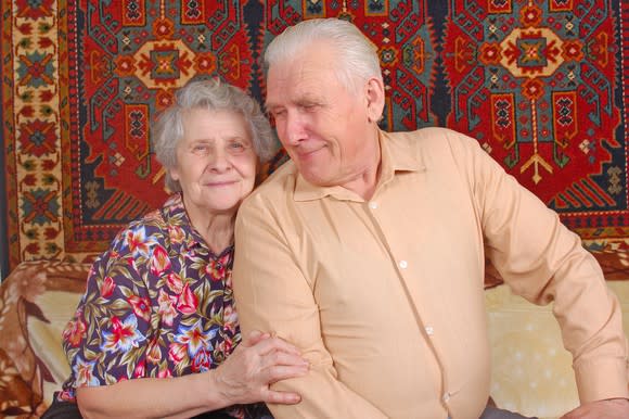 70-something couple sitting on a couch.