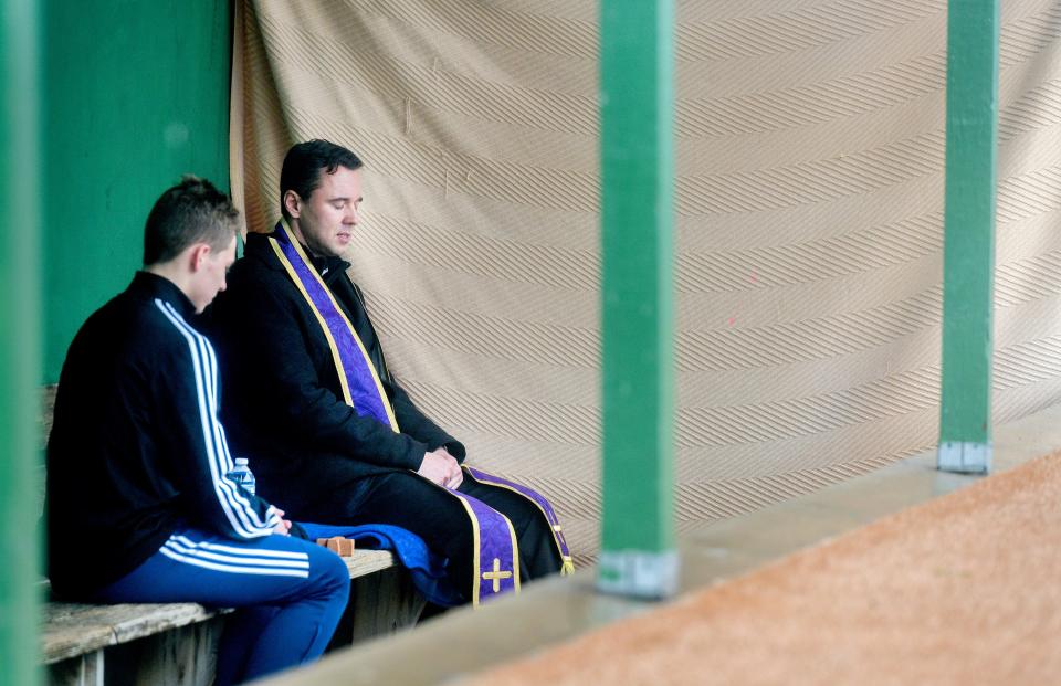 Father Corey Krengiel, right, and Peoria Notre Dame sophomore Brady Socha pray together after Brady’s confession Thursday, March 19 in a baseball dugout behind the high school.
