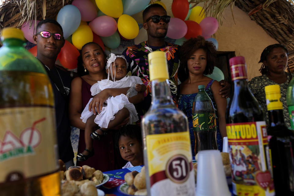 A family with their baptized young daughter family poses for photos during the post-baptism party at their home in the Kalunga quilombo, during the culmination of the week-long pilgrimage and celebration for the patron saint "Nossa Senhora da Abadia" or Our Lady of Abadia, in the rural area of Cavalcante in Goias state, Brazil, Monday, Aug. 15, 2022. (AP Photo/Eraldo Peres)