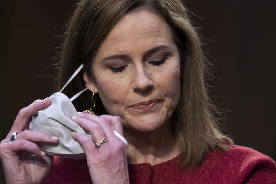 Supreme Court nominee Amy Coney Barrett removes her facemask as she arrives for the second day of her confirmation hearing before the Senate Judiciary Committee on Capitol Hill in Washington, Tuesday, Oct. 13, 2020. (Tom Williams/Pool via AP)