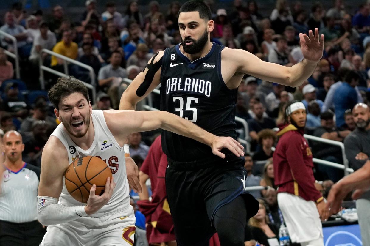 Cleveland Cavaliers' Cedi Osman, left, goes to the basket past Orlando Magic's Goga Bitadze (35) during the first half of an NBA basketball game Thursday, April 6, 2023, in Orlando, Fla. (AP Photo/John Raoux)