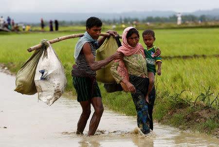 A Rohingya refugee man helps a woman to walk in the water after travelling over the Bangladesh-Myanmar border in Teknaf, Bangladesh, September 1, 2017. REUTERS/Mohammad Ponir Hossain