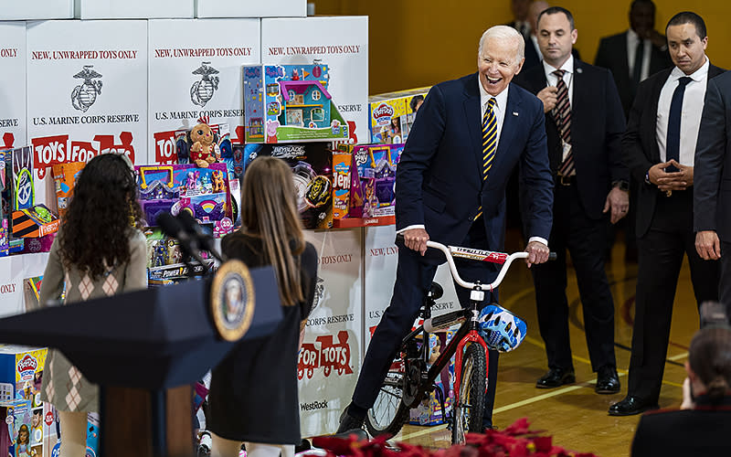 President Biden climbs on a children’s bicycle while participating in a United States Marine Corps Reserve Toys for Tots event at Joint Base Myer-Henderson Hall in Arlington, Va., on Monday. He and his wife participated in sorting donated toys for distribution to families in need ahead of the holidays. <em>Al Drago/UPI Photo</em>