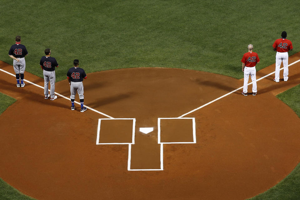 Miembros de los Medias Rojas de Boston y de los Nacionales de Washington escuchan el himno nacional, todos con el número 42 en honor a Jackie Robinson, antes del juego realizado el viernes 28 de agosto de 2020 (AP Foto/Winslow Townson)