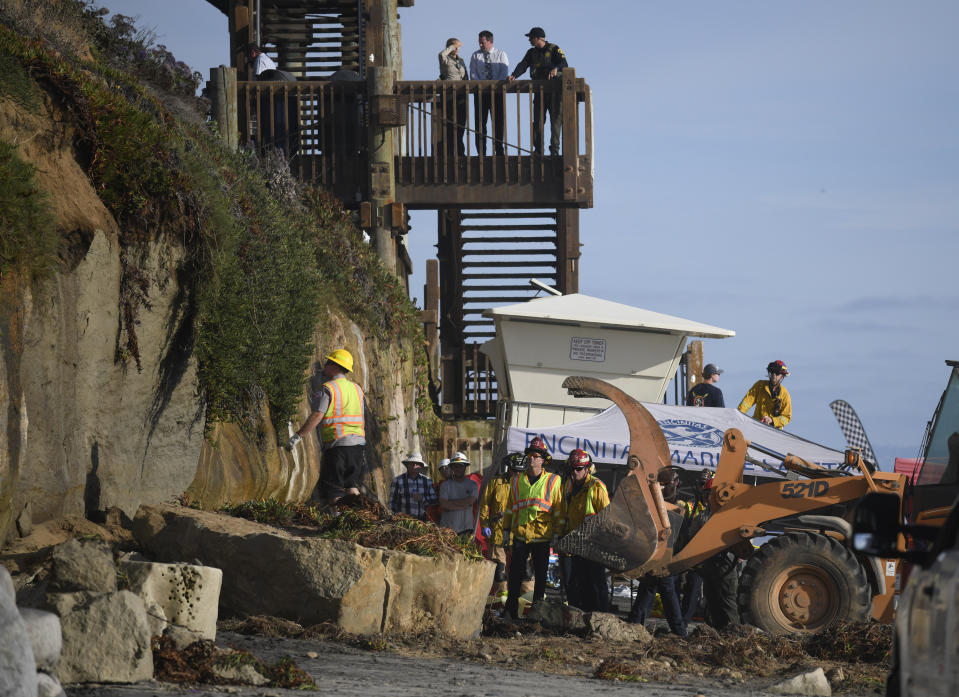 Search and rescue personnel work at the site of a cliff collapse at a popular beach Friday, Aug. 2, 2019, in Encinitas, Calif. At least one person was reportedly killed, and multiple people were injured, when an oceanfront bluff collapsed Friday at Grandview Beach in the Leucadia area of Encinitas, authorities said. (AP Photo/Denis Poroy)