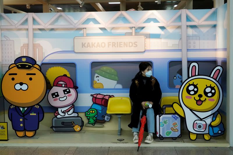 A passenger wearing a mask to prevent contacting the coronavirus sits at a photospot at Seoul Railway Station in Seoul
