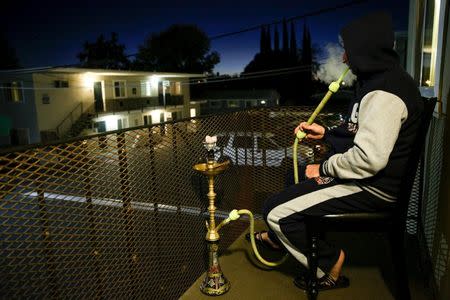 Syrian refugee Mohammed Abd Rabboh smokes hookah at his Sacramento, California apartment, November 16, 2015. REUTERS/Max Whittaker