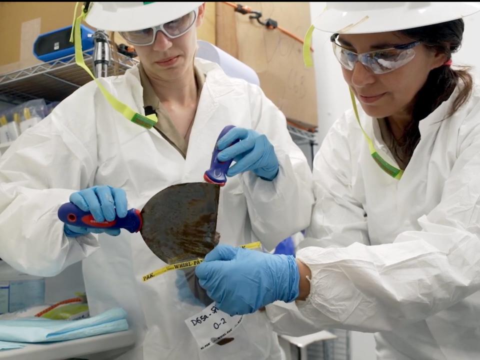 Two researchers put nodule samples into a sample bag.