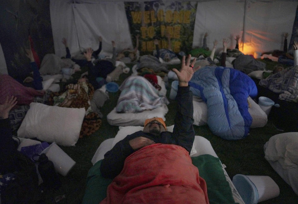 Lorenzo Gonzales, center, and other retreat participants reach their hands to the sky during a breathwork ceremony on Saturday, Oct. 15, 2022, in Hildale, Utah. The session was a part of a three-night ayahuasca ceremony hosted by Hummingbird Church. (AP Photo/Jessie Wardarski)