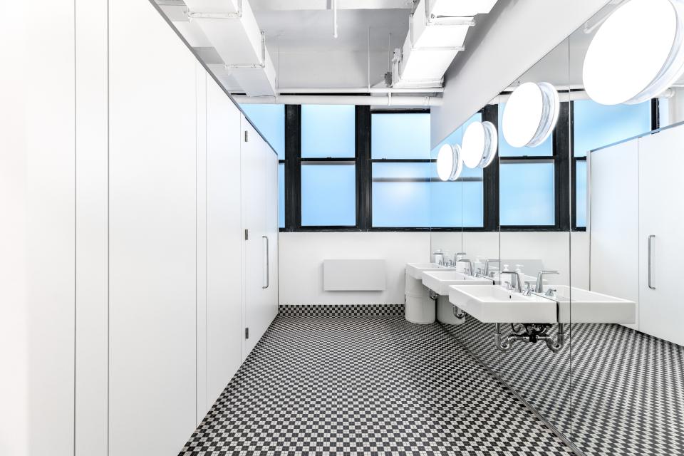 The partitions of the bathroom stalls go all the way to the floor, offering maximum privacy. “We wanted all our spaces to feel generous,” says Bergmann. The faucets were designed by BIG for Kallista; the tile is original to the building.