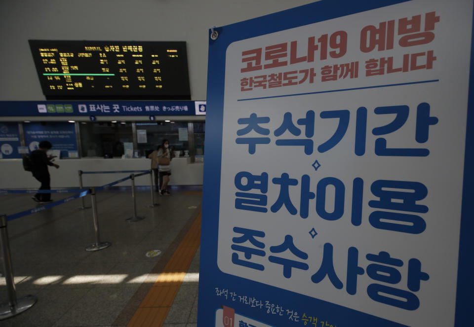 Passengers arrive to buy train tickets near a banner reading "Notice to use the train during the Chuseok holiday. Prevention of COVID-19" at the Seoul Railway Station in Seoul, South Korea, Monday, Sept. 28, 2020. The coronavirus is forcing South Koreans to celebrate their Thanksgiving holiday differently this year. Health authorities are discouraging travel during the five-day Chuseok autumn holidays that begin Wednesday, Sept. 30, 2020 because of concern that people could spread the virus. (AP Photo/Lee Jin-man)