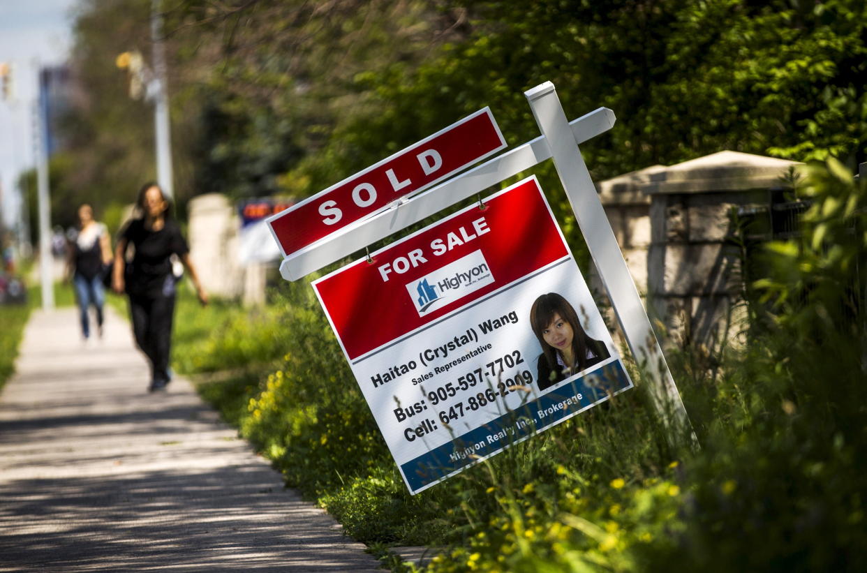 A woman walks towards a "for sale" sign of a home that has been sold in Toronto. (REUTERS/Mark Blinch)