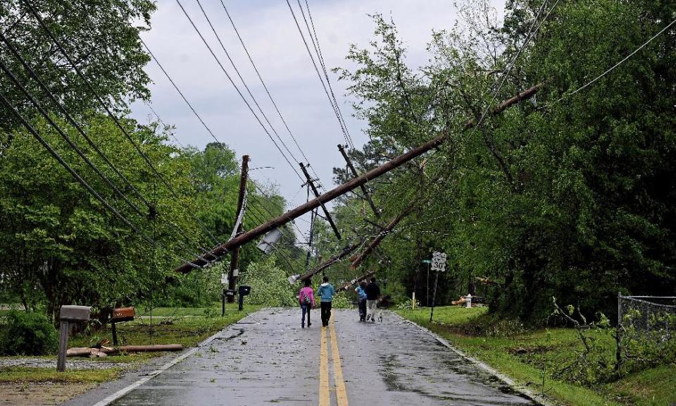 Residents walk along a street in Tupelo, Miss., Monday, April 28, 2014. Tornados flattened homes and businesses, flipped trucks over on highways and injured numerous people in Mississippi and Alabama on Monday as a massive, dangerous storm system passed over several states in the South, threatening additional twisters as well as severe thunderstorms, damaging hail and flash floods. (AP Photo/The Daily Mississippian, Thomas Graning)