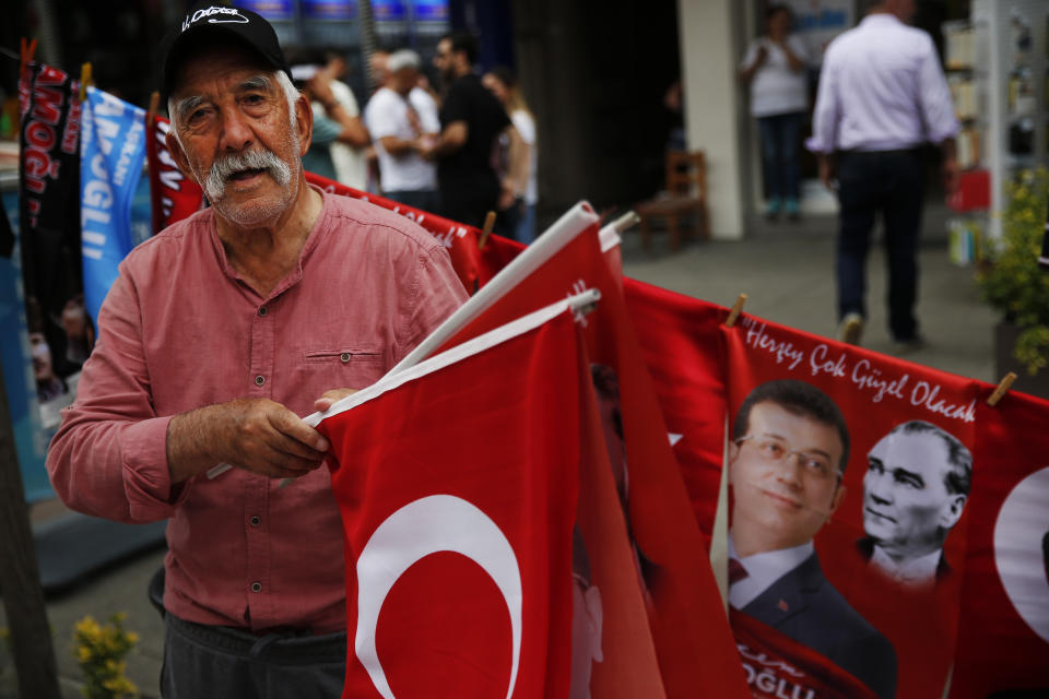 In this Wednesday, June 19, 2019 photo, a vendor sells flags with pictures of Ekrem Imamoglu, candidate of the secular opposition Republican People's Party, or CHP, and modern Turkey's founder Mustafa Kemal Ataturk, during a rally in Istanbul. Millions of voters in Istanbul go back to the polls for a controversial mayoral election re-run Sunday, as President Recep Tayyip Erdogan's party tries to wrest back control of Turkey's largest city. (AP Photo/Lefteris Pitarakis)