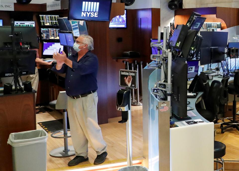 A trader wearing a mask reacts at the closing bell, on the first day of in person trading since the closure during the outbreak of the coronavirus disease (COVID-19) on the floor at the New York Stock Exchange (NYSE) in New York, U.S., May 26, 2020. REUTERS/Brendan McDermid