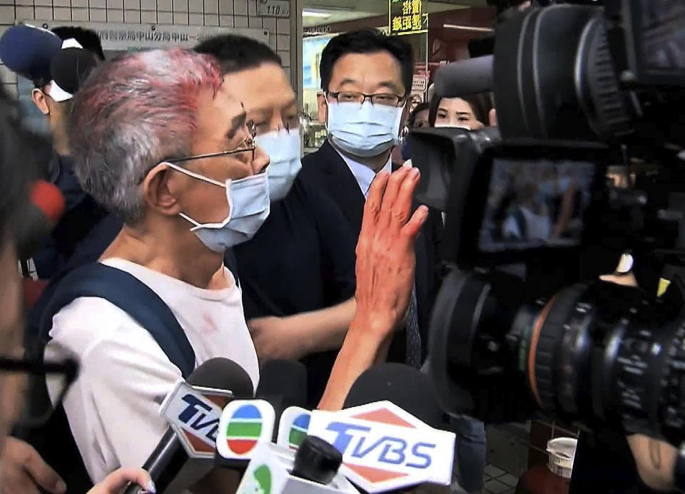 In this image made from video, Lam Wing-kee, left, founder of Hong Kong’s Causeway Bay Book shop speaks to journalists in Taipei Tuesday, April 21, 2020. Lam was attacked by unidentified man who threw red paint at him on Tuesday morning in Taipei. According to police, an unknown man in mask and dark clothes suddenly came to throw red paint at Lam while he was alone at a coffee shop. (EBC via AP)