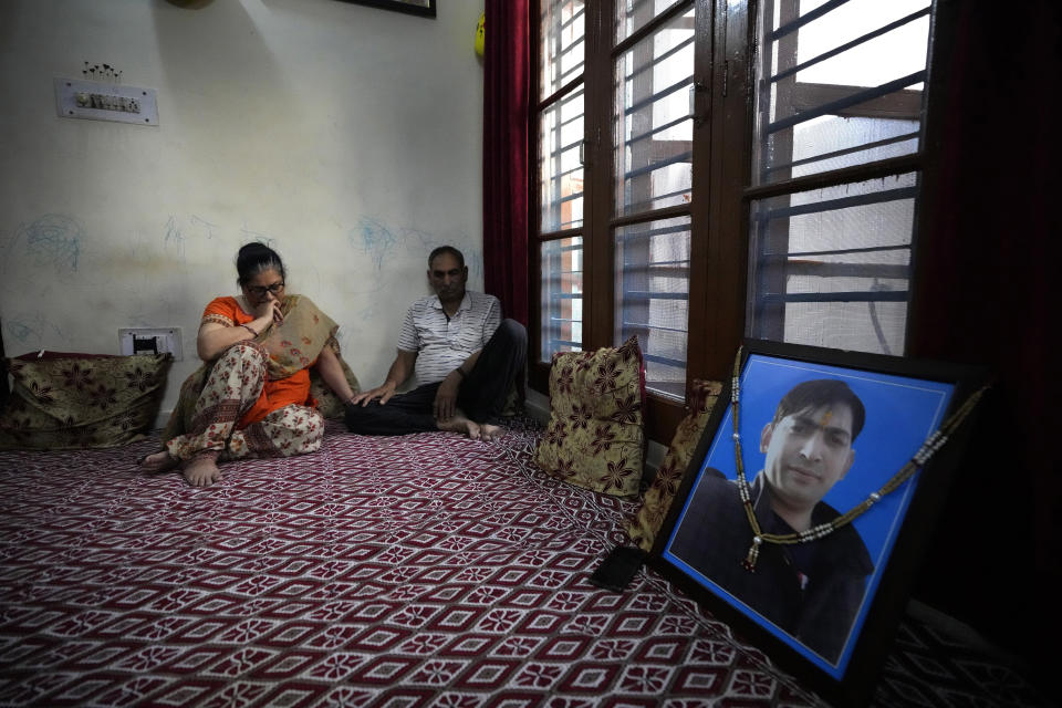 Usha Bhat, left, and Bitta Ji Bhat mourn by a photograph of their son Rahul Bhat at their residence in Jammu, India, June 11, 2022. Rahul Bhat, a Hindu revenue clerk, was fatally shot inside his office in Kashmir Valley in May. Two days later, police said they had shot dead the anti-India rebels responsible in a gunfight. That hasn't eased the deep mourning of Bhat's parents who have yet to reconcile with the death of their son. (AP Photo/Channi Anand)