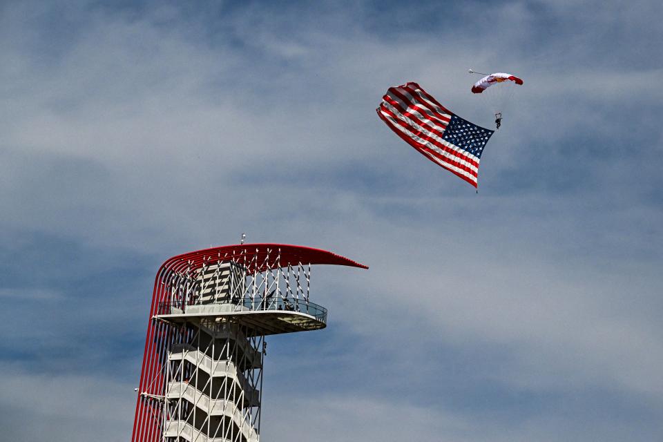 Un parachutiste brandit un drapeau américain avant le départ du Grand Prix de Formule 1 des États-Unis 2023 sur le Circuit des Amériques à Austin, Texas, le 22 octobre 2023. (Photo de Chandan Khanna/AFP) (Photo de Chandan Khanna/AFP via Getty Images)