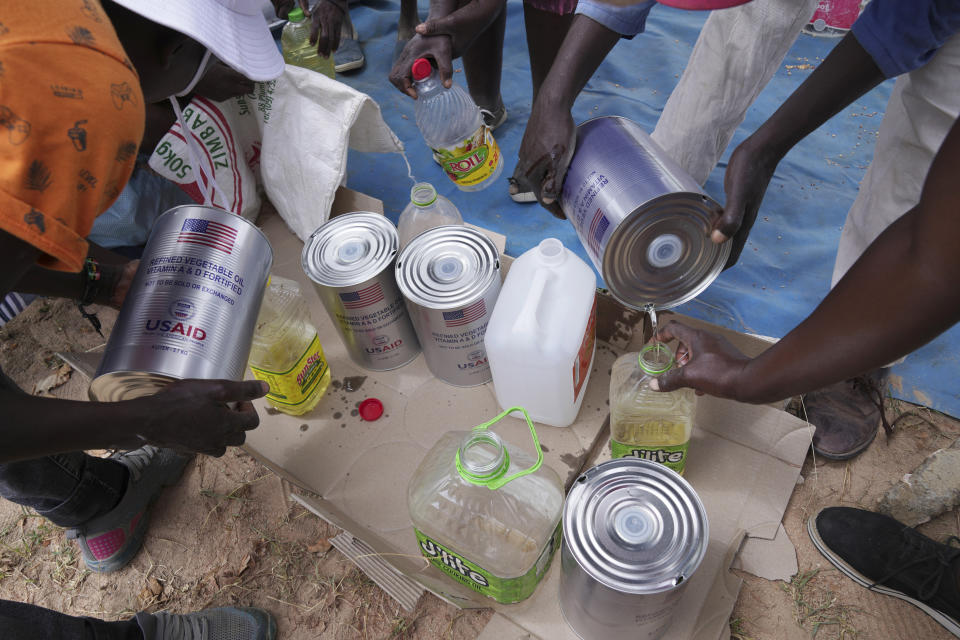 Women share cooking oil during a food distribution Mangwe district in southwestern Zimbabwe, Friday, March, 22, 2024. A new drought has left millions facing hunger in southern Africa as they experience the effects of extreme weather that scientists say is becoming more frequent and more damaging. (AP Photo/Tsvangirayi Mukwazhi)